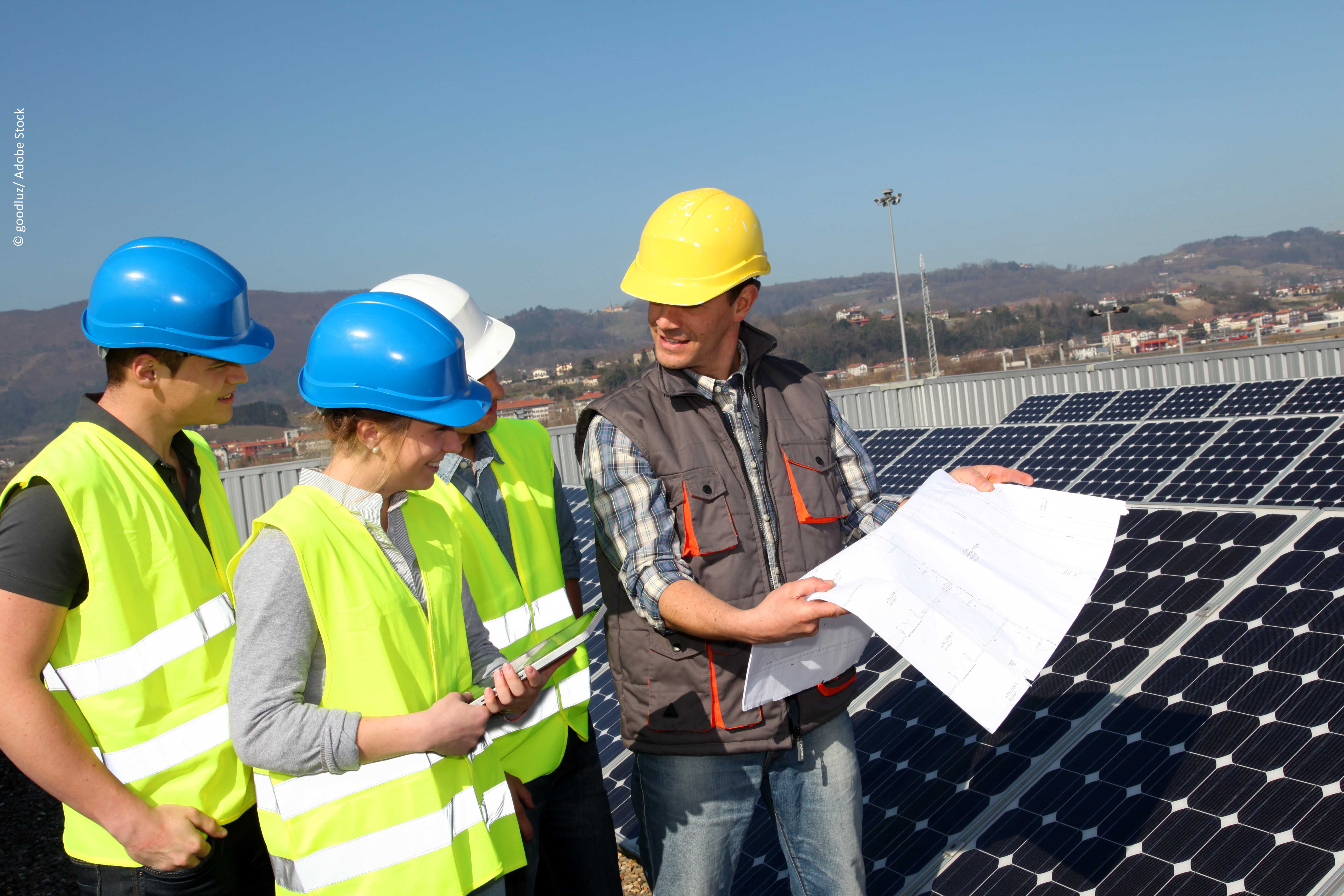 Mitarbeiter zeigt Schülerinnen und Schülern Photovoltaikanlage