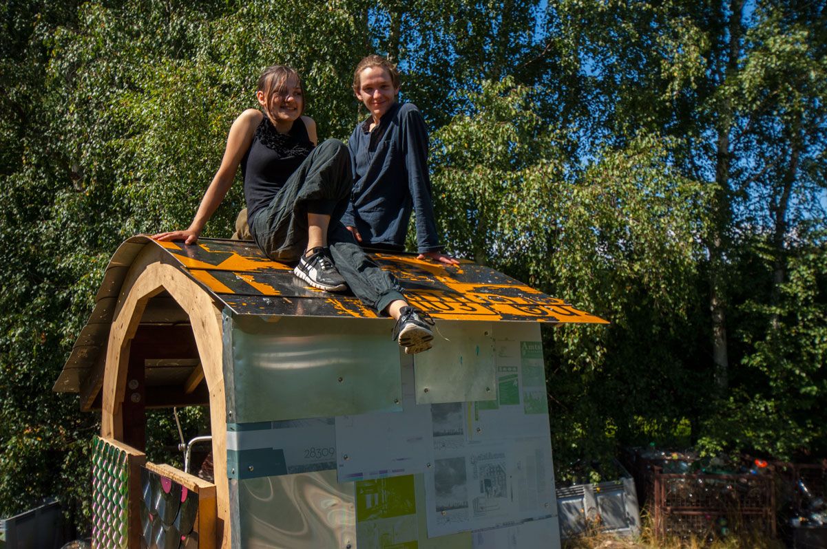 Zwei Jugendliche sitzen auf einem Bauwerk aus Recyclingmaterial