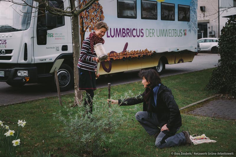 Zwei Frauen vor dem LUMBRICUS-Bus nehmen eine Bodenprobe