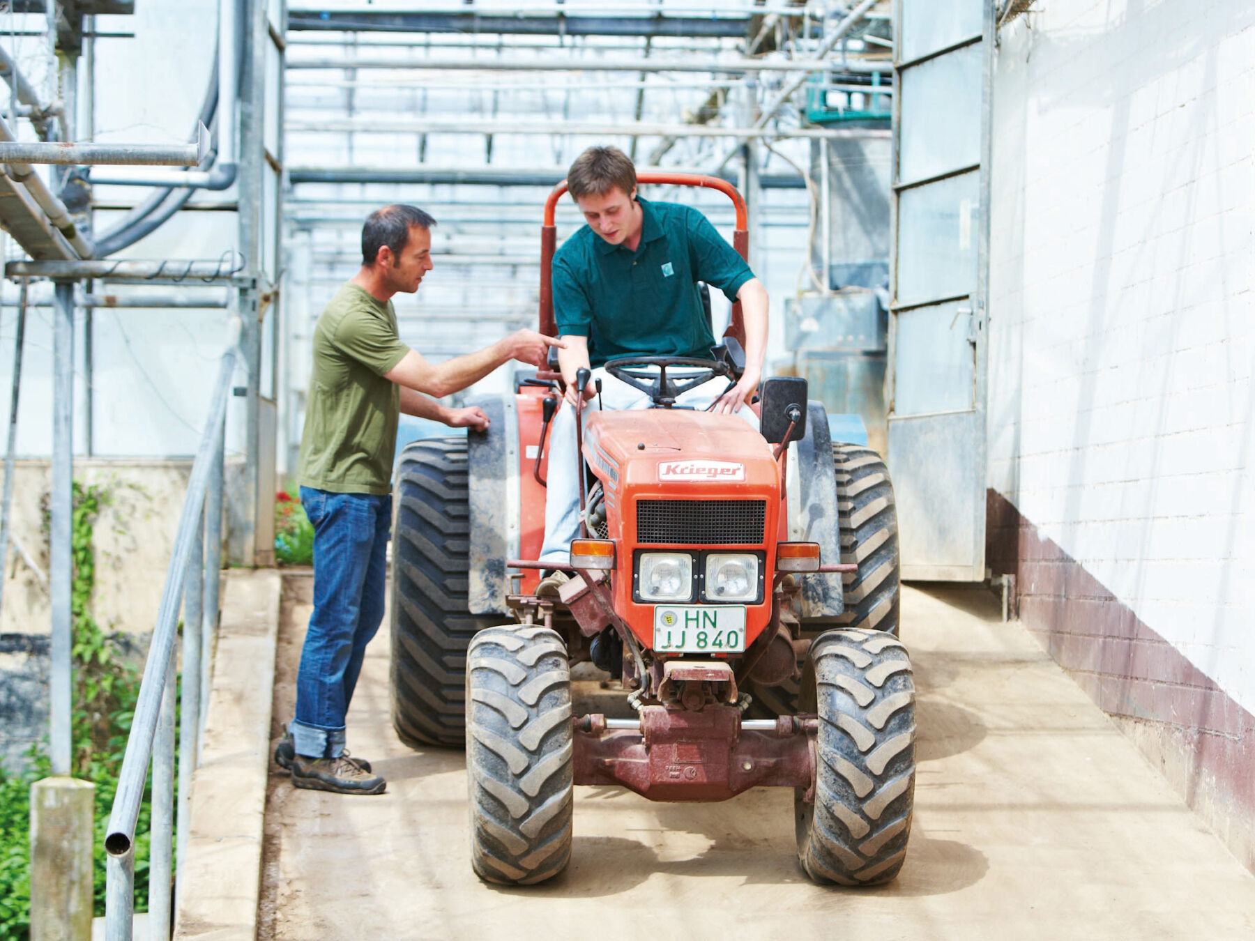 Auszubildender sitzt auf Traktor und wird angelernt