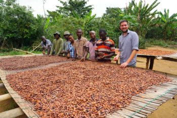 Kakaobauern in Afrika vor geernteten Kakaobohnen