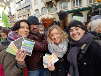drei Frauen halten Postkarten vom Grüner Strom Label und Gas Label hoch