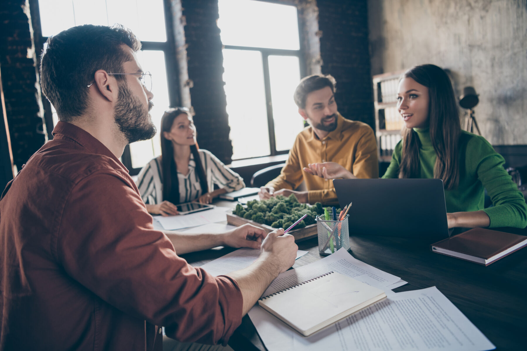 Positive joyful marketers practice experienced students have conversation, communication discus start-up development progress innovation planning sit desk table in workstation