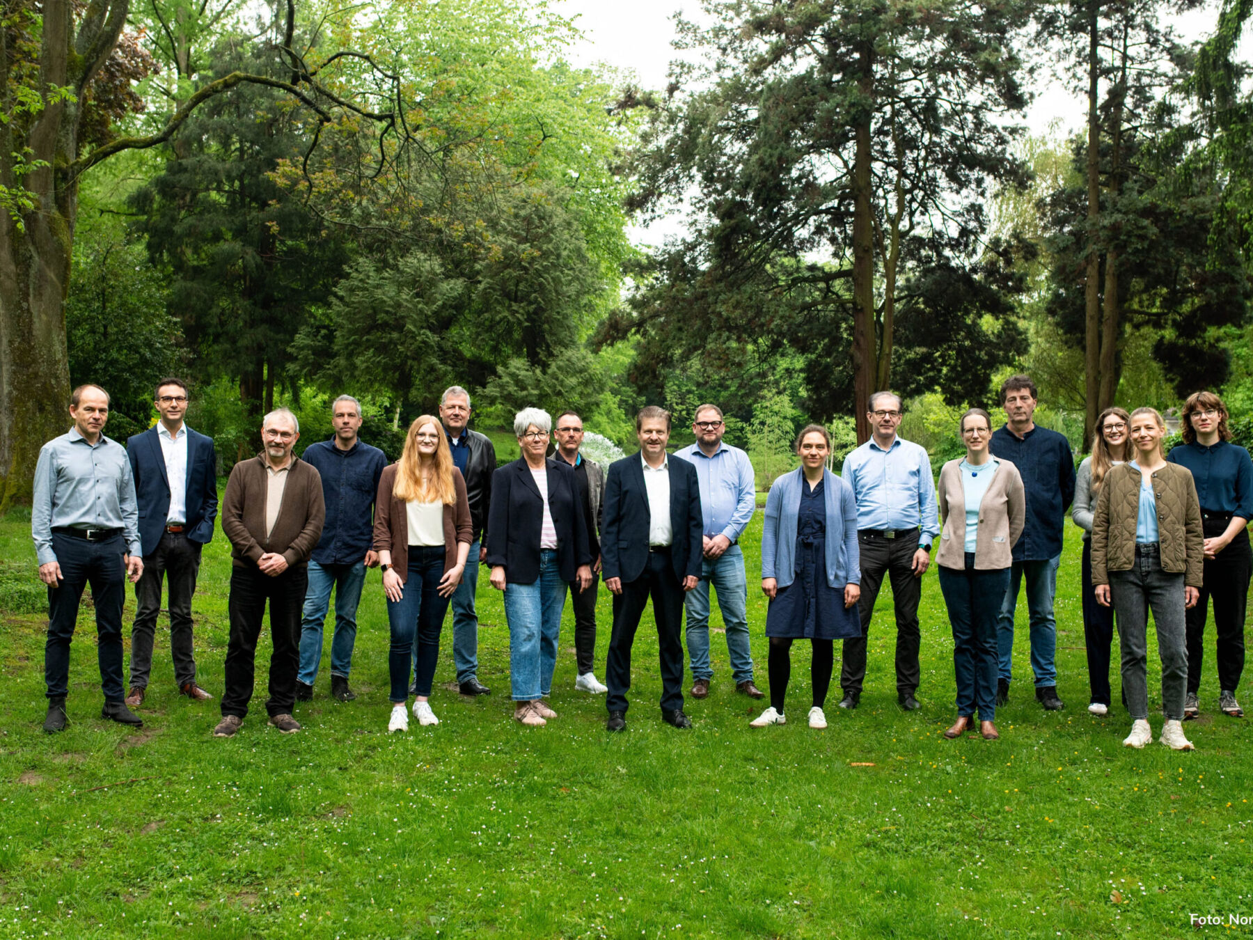 Team der Energieagentur, 17 Personen, stehen auf einer Wiese vor Bäumen