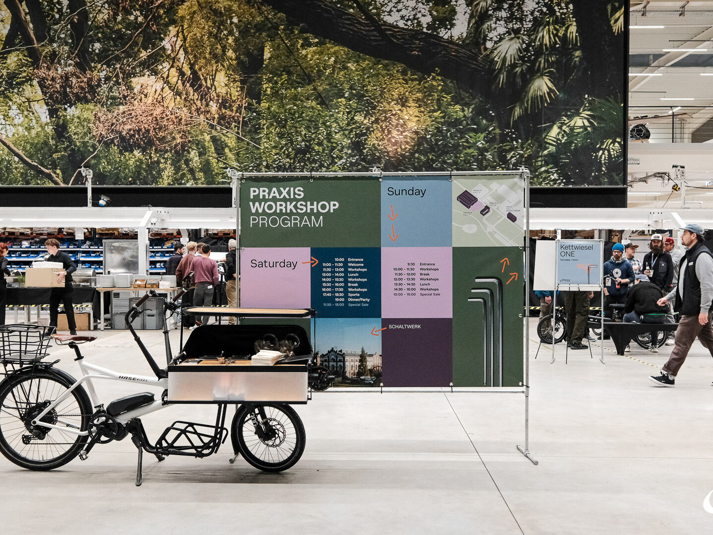 Eine Fahrradmesse, im Vordergrund ein Lastenrad und eine Tafel zum Workshop-Programm.