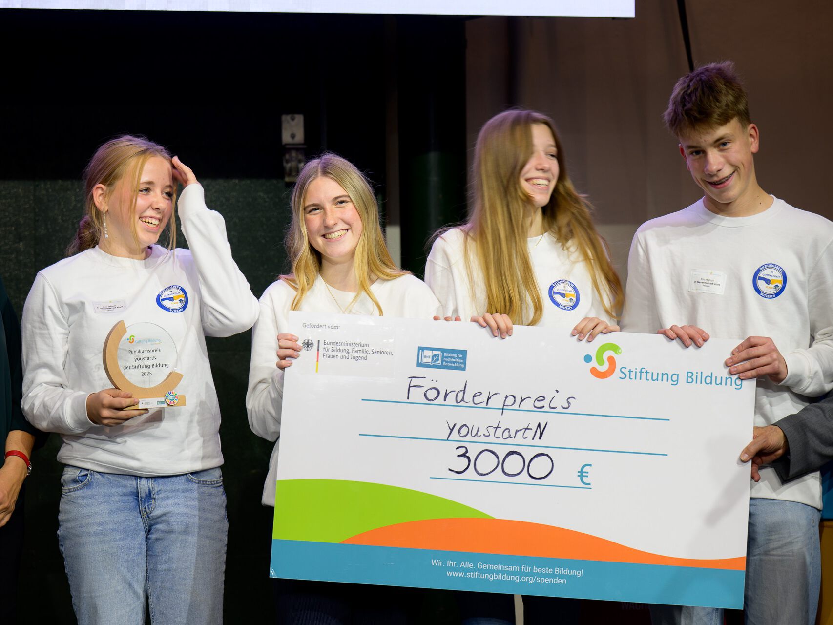 Vier junge Menschen halten ein Schild 
