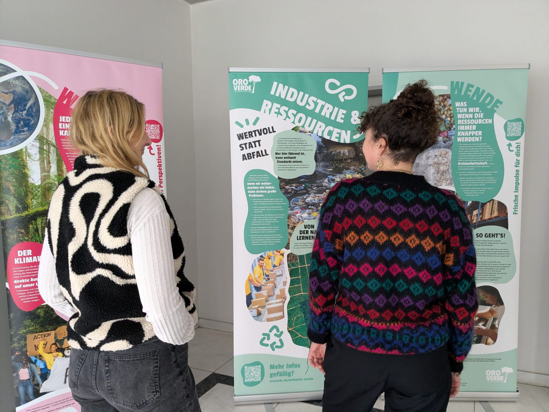 Zwei Frauen stehen vor Ausstellungsplakaten.
